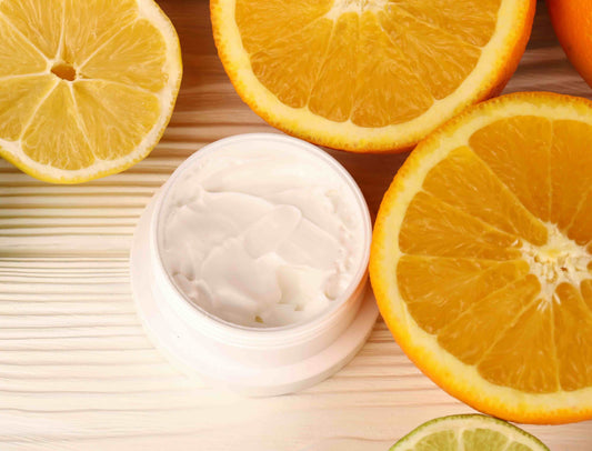 Photo of oranges surrounding a bottle of skin cream to demonstrate the importance of vitamin C in skin care.