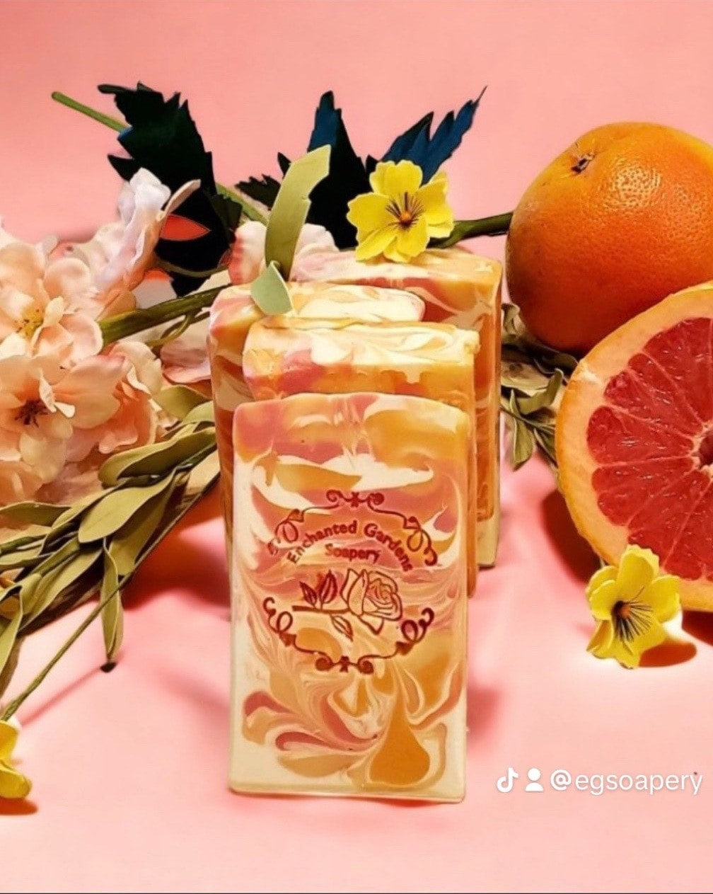 A bar of Grapefruit Mandarin Soap with a floral pattern, surrounded by grapefruits and flowers.