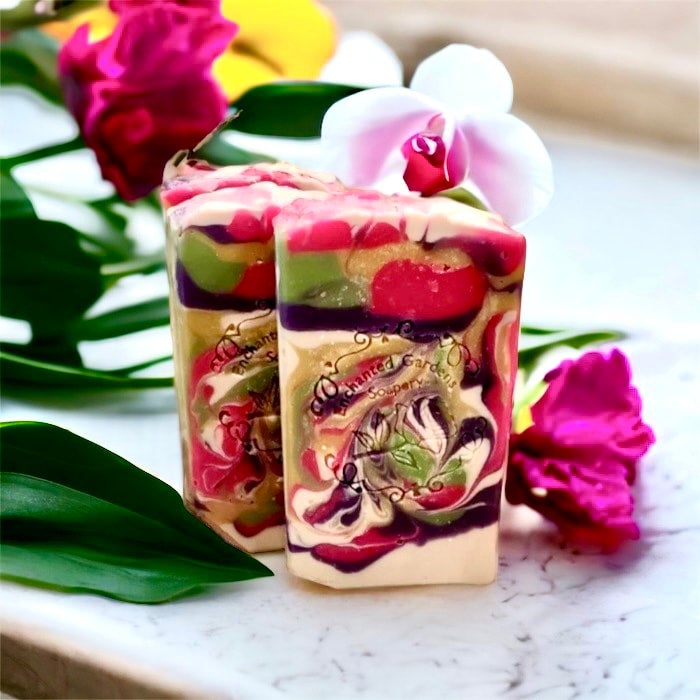 A bar of soap with a colorful, floral pattern, placed on a surface with a pink flower beside it.